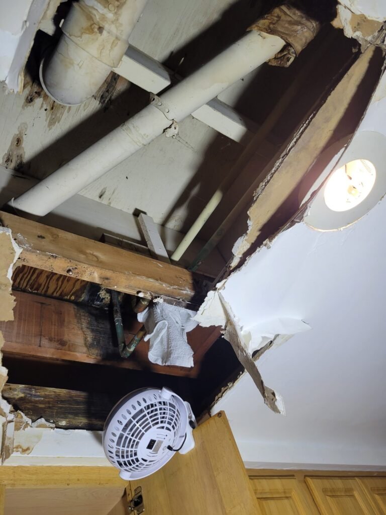 Ceiling opened below a bathroom to trace a water leak in Germantown, MD