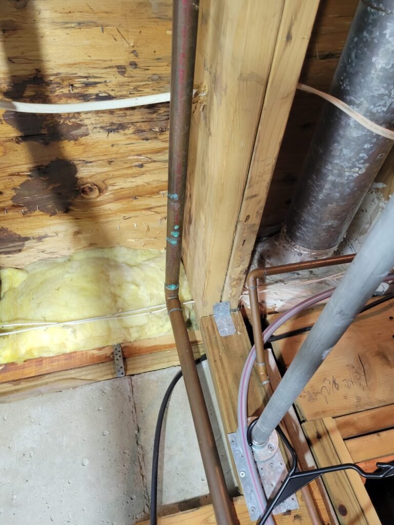 Old water pipes in a basement ceiling before replacement in Lanham, MD