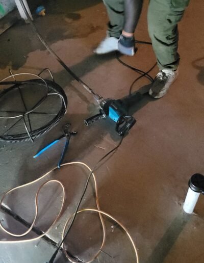 Technician running drain cleaning equipment in a basement in Upper Marlboro, MD