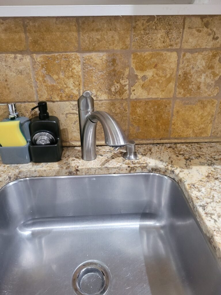 Old kitchen faucet on a granite countertop before replacement in Washington, DC
