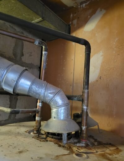 Water heater flue vent and gas line in a basement before repair in Glenarden, MD